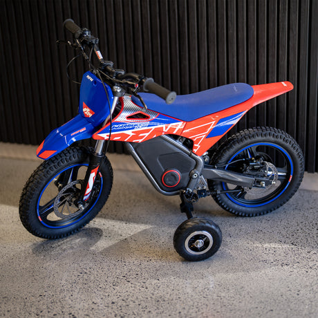 Small red and blue dirt bike on a gray surface with a dark background